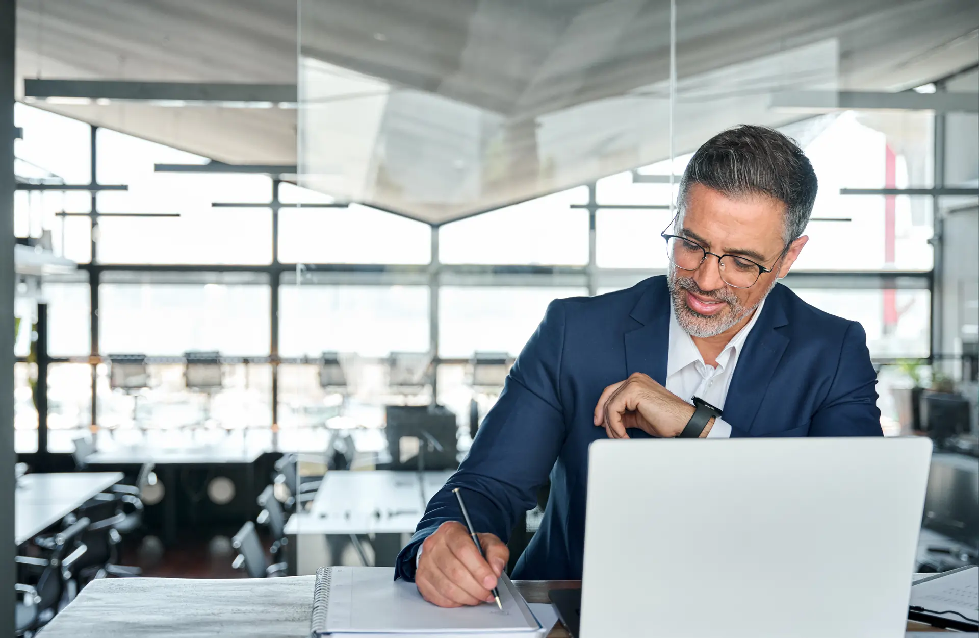 smiling man sitting at desk in front of laptop computer