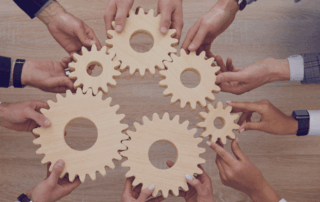 arms in professional attire holding various sized cogwheels